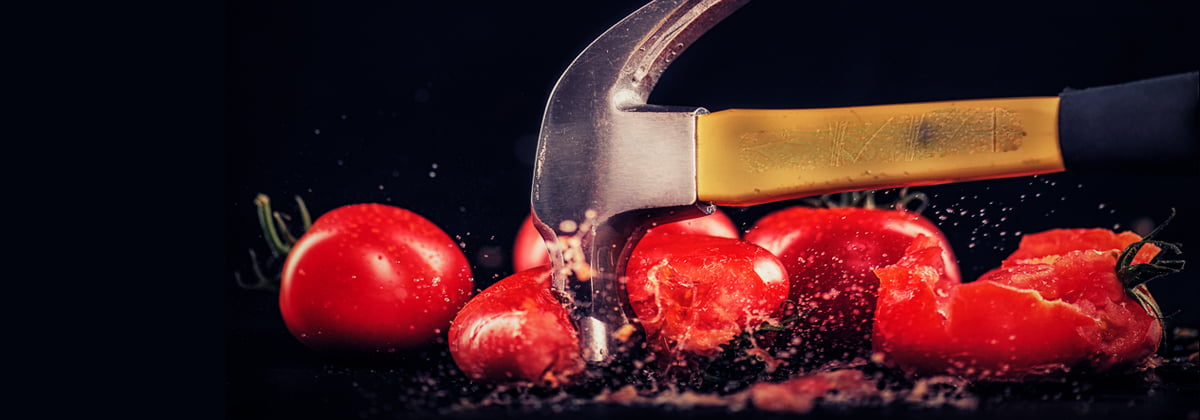 Foto de um martelo amassando tomates.