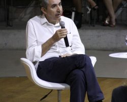 Foto de João Lopes Guimarães Junior falando ao microfone .