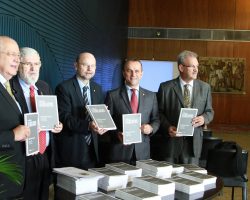 Foto com cinco homens da esquerda para a direita: Luiz Carlos Hauly, Luiz Couto, Bohn Gass, Helder Salomão e Geraldo Resende. Ambos seguram um caderno legislativo.