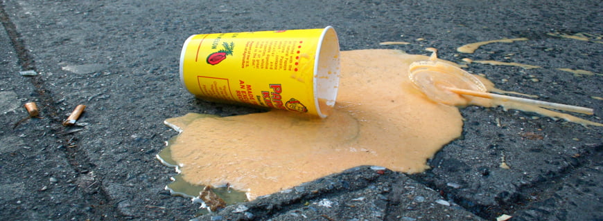 Imagem de uma copo amarelo com bebida derramada ao chão.