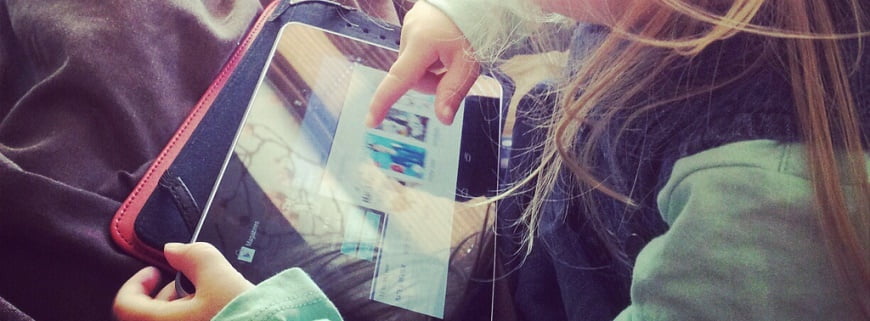 Foto de uma menina mexendo em um tablete.