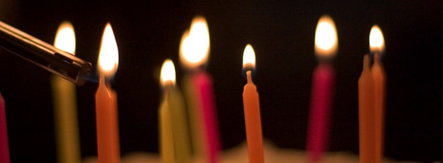 Foto de velas de aniversario vermelhas sendo acessas.