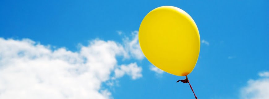 Foto de uma balão amarelo em direção ao céu.