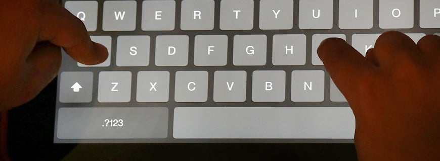 Foto de mão digitando em um teclado de um tablete para representar a publicidade infantil na internet
