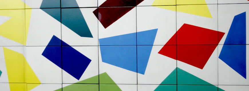 Foto de uma pintura na parede abstrata, várias formas poligonais de tons de cores azuis, vermelhas, amarelas e preto.