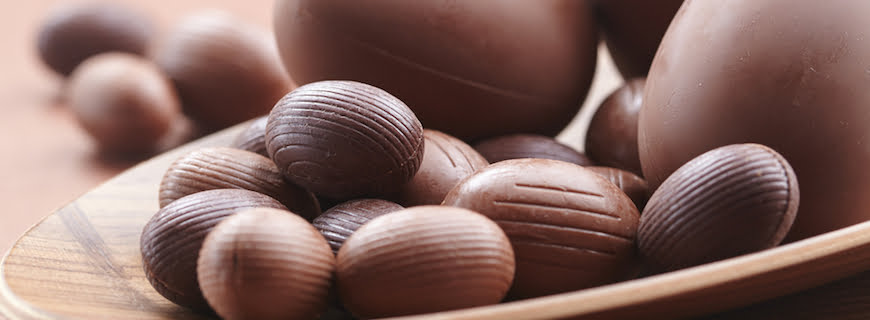 Foto de ovos de chocolate em cima de uma mesa.