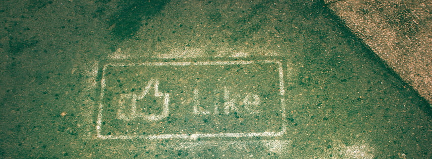 Foto de um grafite feito em um chão verde, está escrito like no grafite.