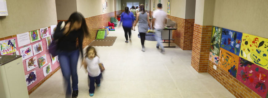 Foto de um corredor, pessoas caminham no corredor.
