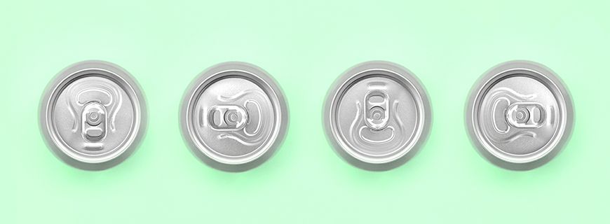 Foto de cima de quatro latas de cerveja, em fundo verde