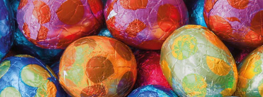 Foto de vários ovos de chocolates embrulhados em papeis multicoloridos.