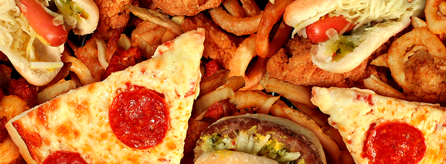 Foto de várias comidas gordurosas como: pizza, Hambúrguer, cachorro quente e mais algumas outras.