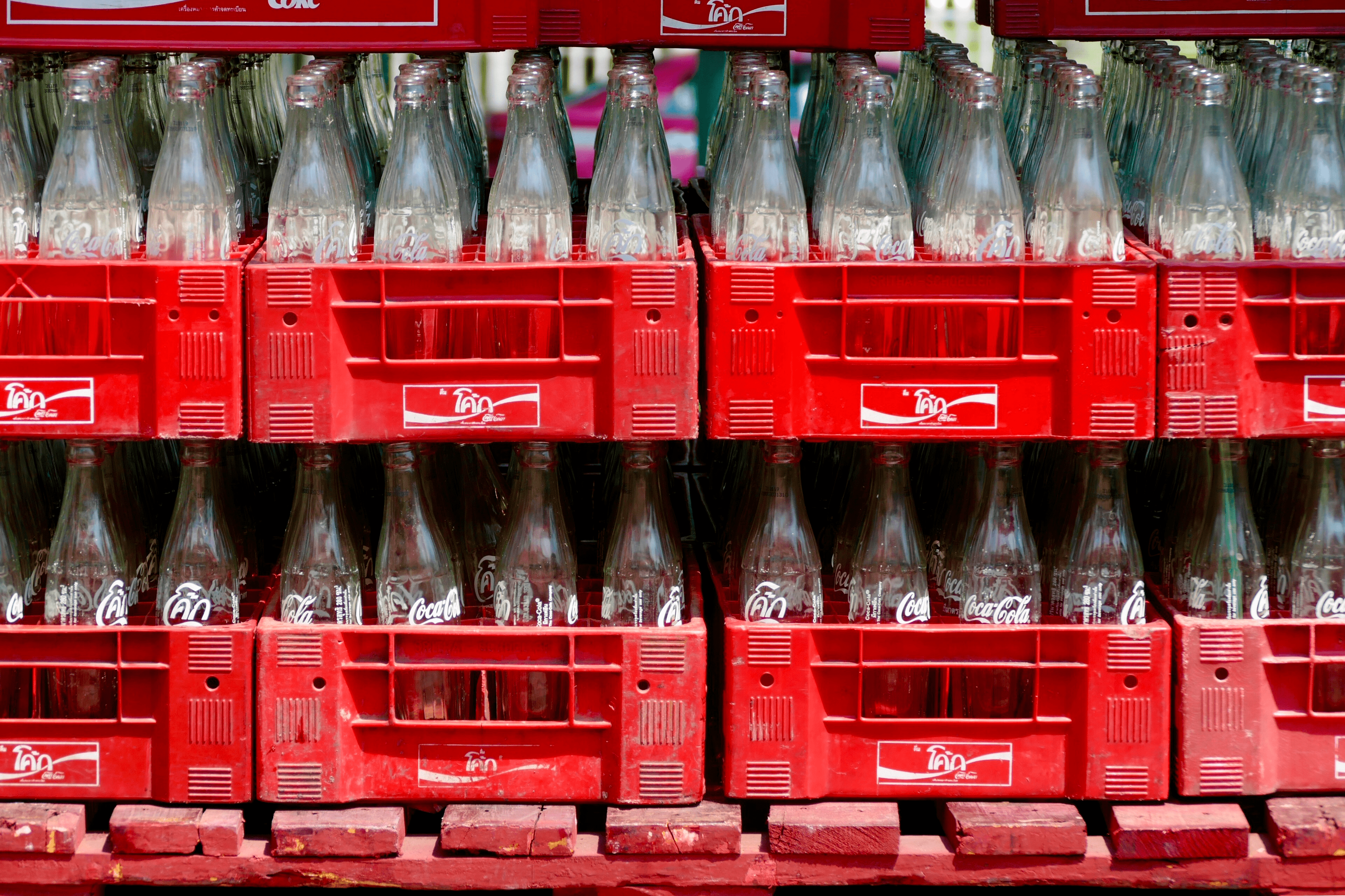 Foto de vários engradados com garrafas de refrigerante Cocacola, os engradados estão empilhados um em cima do outro.