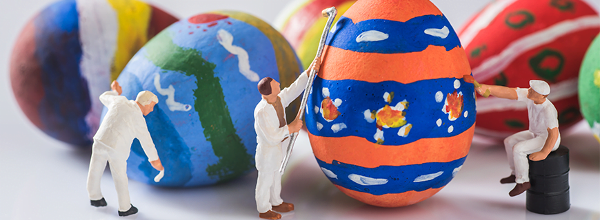 Foto em que miniaturas de pessoas pintam ovos coloridos