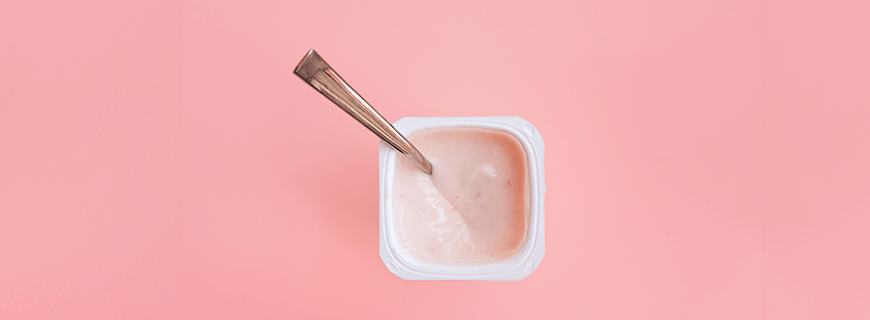 Foto de pote de iogurte de morango, em fundo rosa