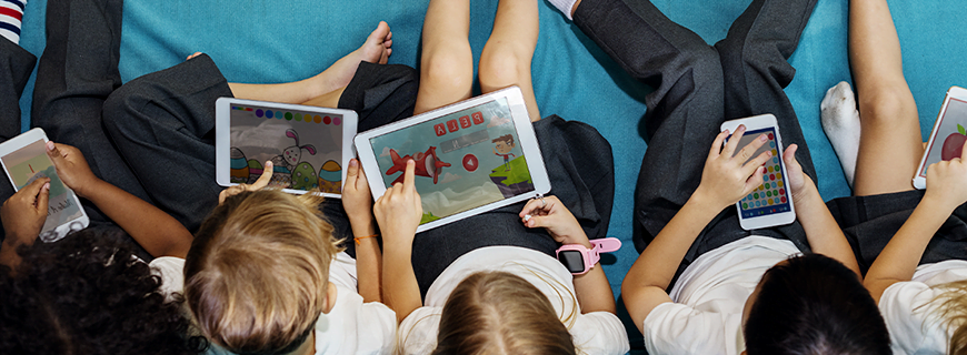 foto de várias crianças sentadas no chão mexendo em celulares e tablets como imagem de apoio ao texto sobre internet segura para crianças