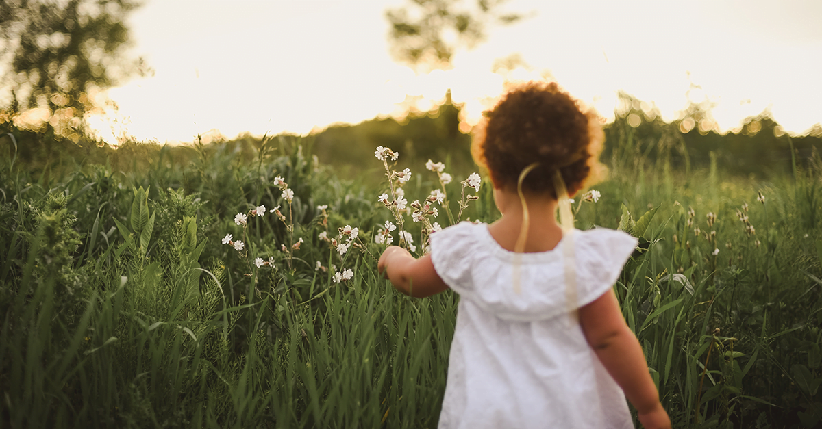 foto de uma menina de costas em um campo de flores como imagem de apoio ao texto sobre meninas e publicidade infantil