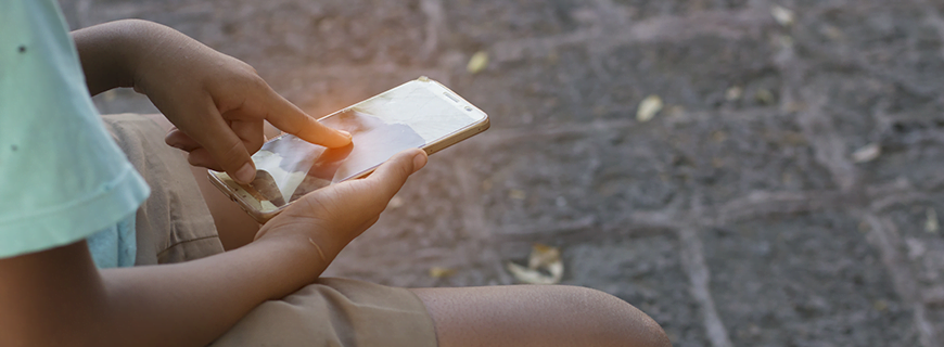 foto em detalhe das mãos de uma criança mexendo em um celular como imagem de apoio ao texto sobre privacidade de crianças e adolescentes