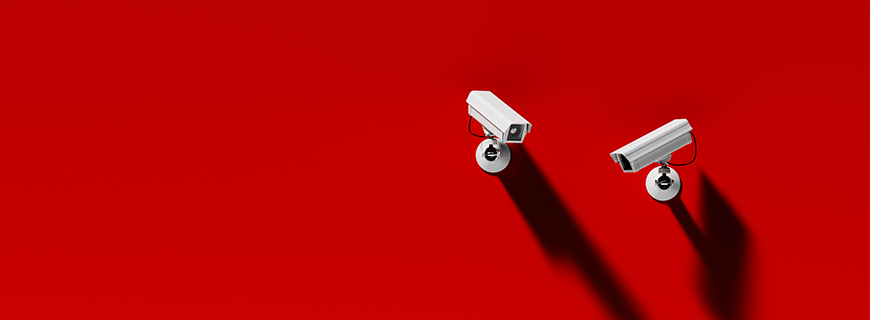 em fundo vermelho, foto de duas câmeras de segurança como imagem de apoio ao texto sobre dados pessoais por reconhecimento facial