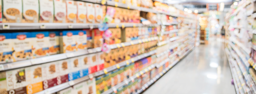 foto de um corredor de supermercado desfocado com caixas de sucrilhos e cereais nas estantes como imagem de apoio ao texto sobre publicidade infantil com apologia ao uso de armas