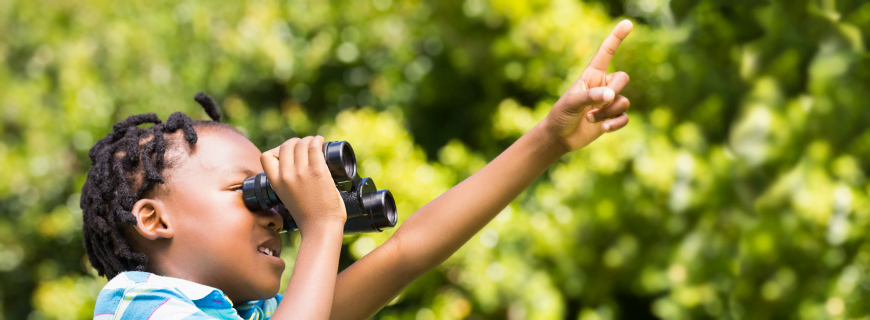 foto de uma criança com um binóculos e apontando para o alto em um parque como imagem de apoio ao texto de retrospectiva de 2021 sobre proteger infâncias de exploração comercial