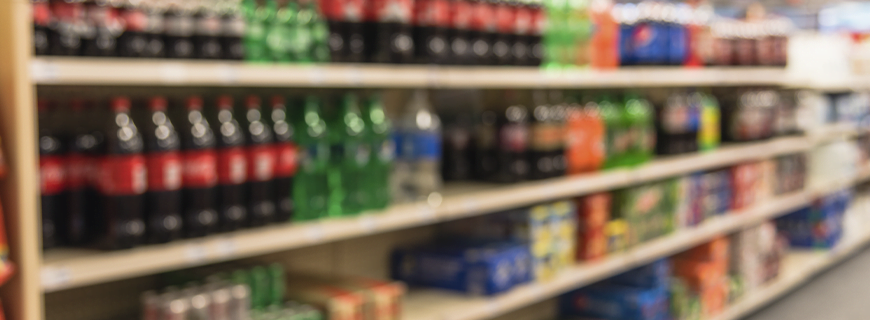 foto desfocada de uma prateleira de mercado com bebidas artificiais açucaradas como imagem de apoio ao texto sobre Organização Mundial da Saúde