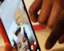 foto em detalhe de um celular segurado por uma criança que brinca com filtros em um aplicativo de fotos e vídeos como imagem de apoio ao texto sobre Criança e Consumo notifica TikTok
