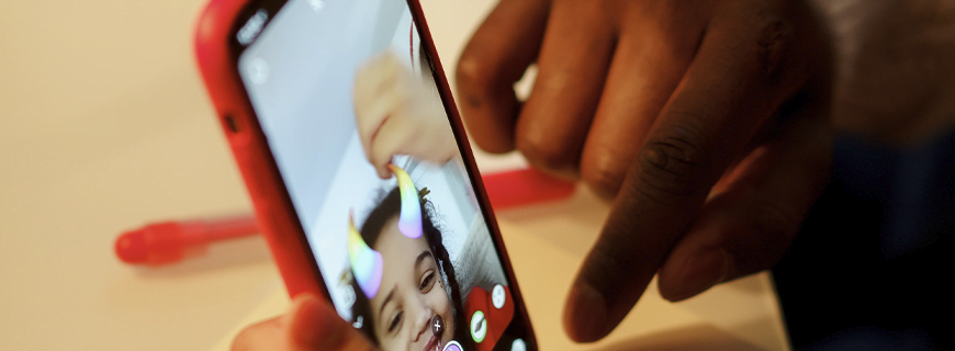 foto em detalhe de um celular segurado por uma criança que brinca com filtros em um aplicativo de fotos e vídeos como imagem de apoio ao texto sobre Criança e Consumo notifica TikTok
