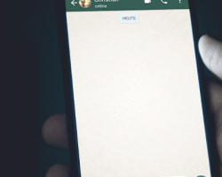 foto em detalhe de uma mão segurando um celular com uma conversa do WhatsApp aberta como imagem de apoio ao texto sobre uso de dados de crianças e adolescentes pelo WhatsApp