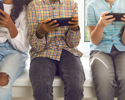 foto de cinco crianças e adolescentes sentadas lado a lado mexendo em celulares como imagem de apoio para o texto sobre a pesquisa TIC Kids Online Brasil 2021