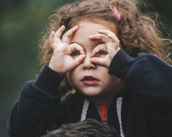 foto de uma criança com as mãos no rosto fingindo ser um binóculo como imagem de apoio do texto sobre direitos das crianças on-line sejam prioridade do Poder Público