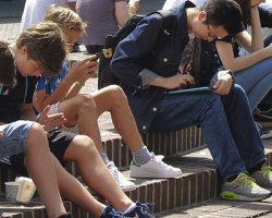 foto de adolescentes e crianças sentados em uma escada no chão e todos mexendo em seus celulares como imagem de apoio ao texto sobre prorrogação no prazo da Tomada de Subsídios